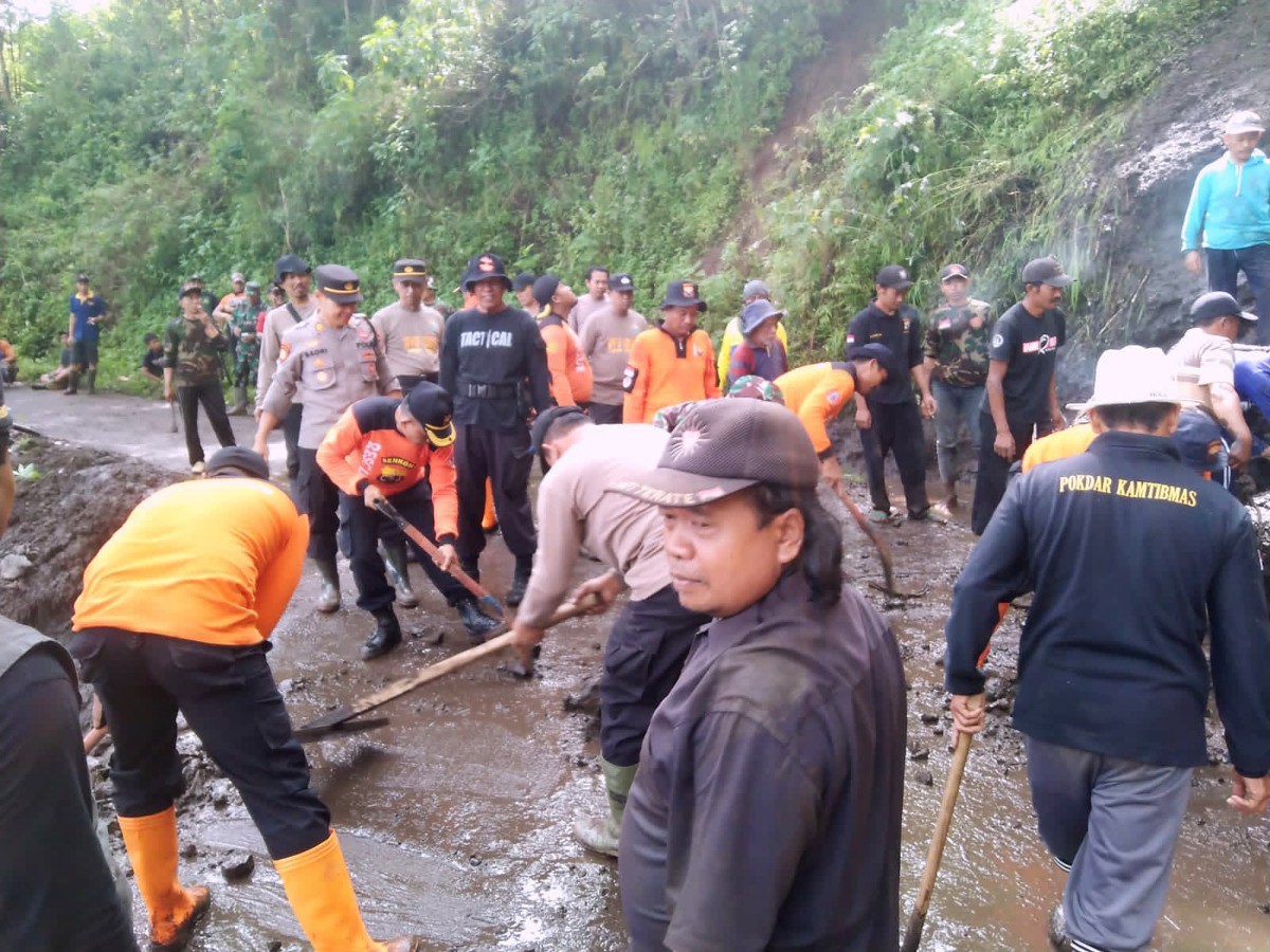 Petugas gabungan berusaha membersihkan material longsor yang disebabkan hujan deras dengan intensitas tinggi. (foto: Polsek Sambit for jatimnow.com)