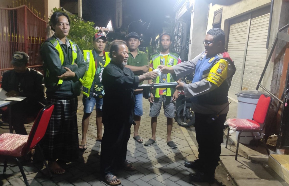 Anggota Bhabinkamtibmas Polsek Rungkut saat memberikan bantuan berupa borgol dan tongkat kepada warga Rungkut Kidul RW 01, Surabaya (Foto: Polsek Rungkut for jatimnow.com)