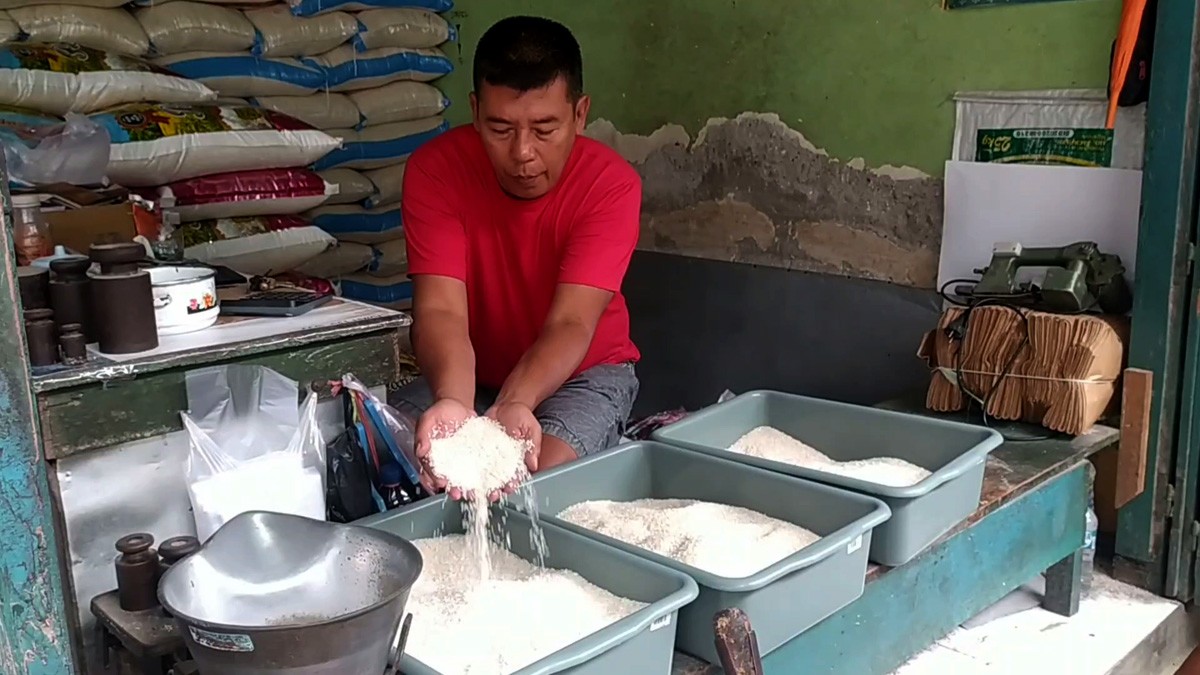 Pedagang di PCN Jombang menunjukkan beras medium yang harganya naik sejak November 2022 silam. (foto: Elok Aprianto/jatimnow.com)