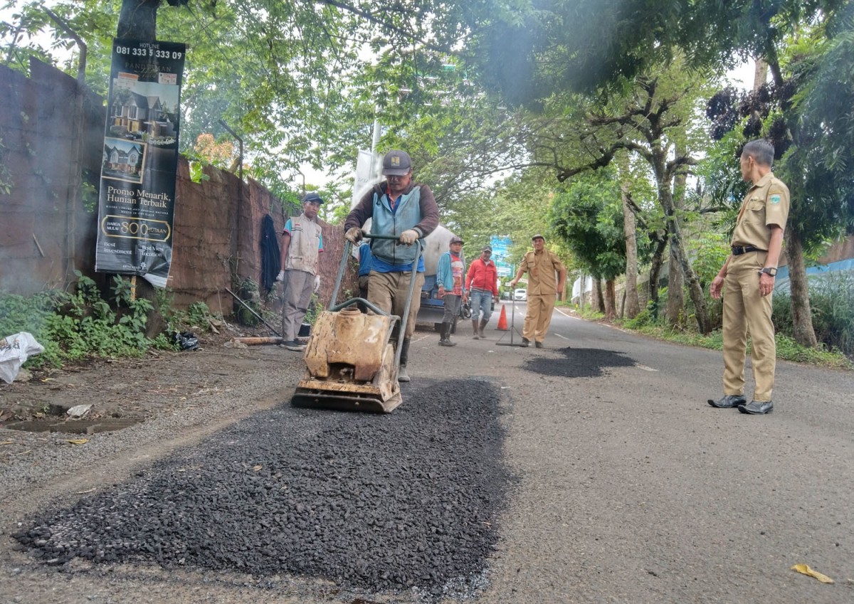 Petugas DPUPR Kota Batu sedang menambal jalan berlubang (Foto: Galih Rakasiwi/jatimnow.com)