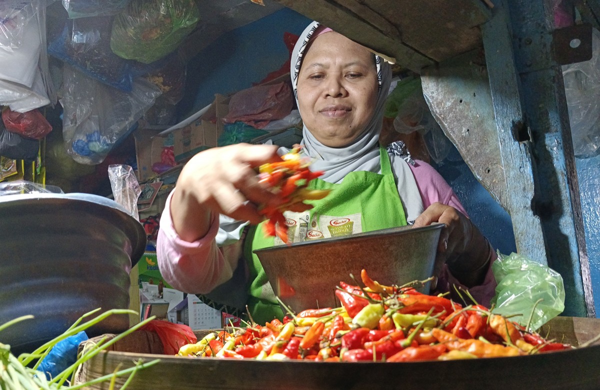 Pedagang cabai rawit merah di Pasar Keputran Surabaya menakar dagangannya. (foto: Rama Indra Surya/jatimnow.com)