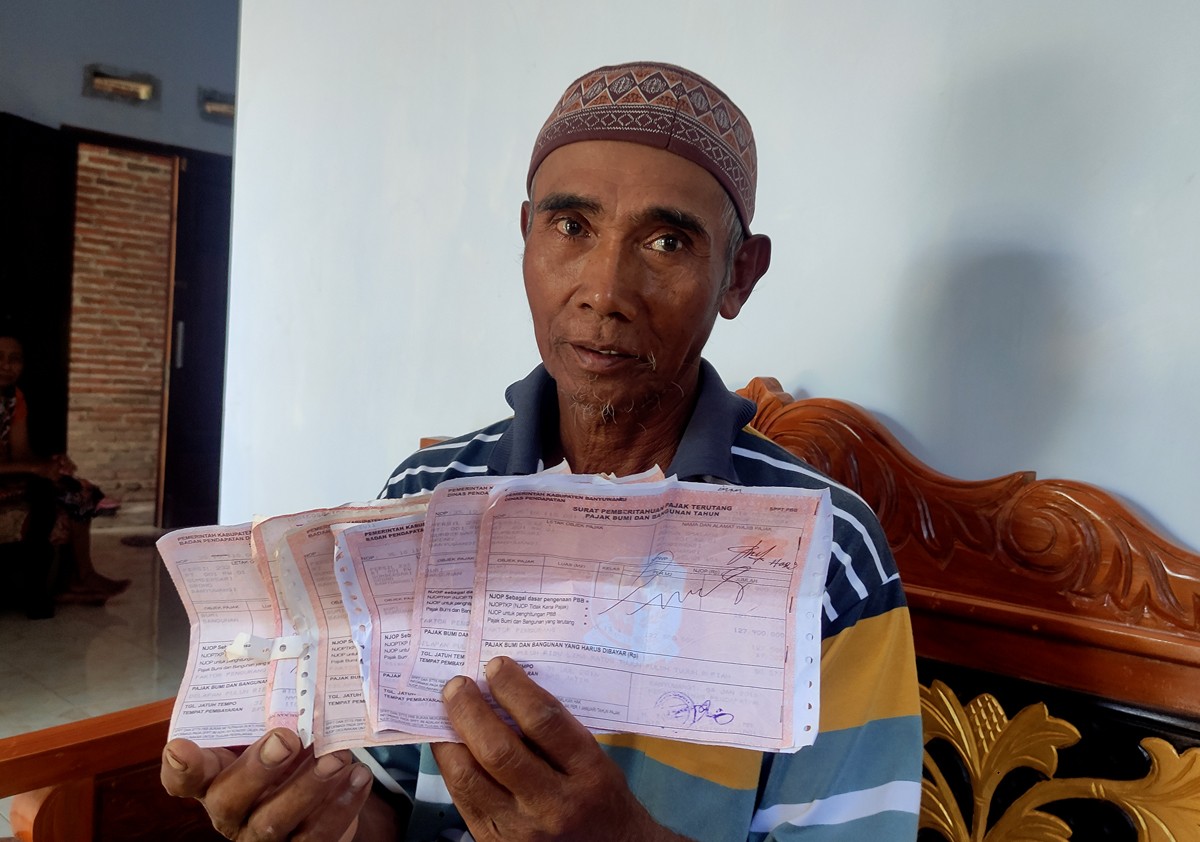 Imam Hajadi (65) menunjukkan SPPT PBB bertanda tangan dan berstempel lunas. (foto: Eko Purwanto/jatimnow.com).