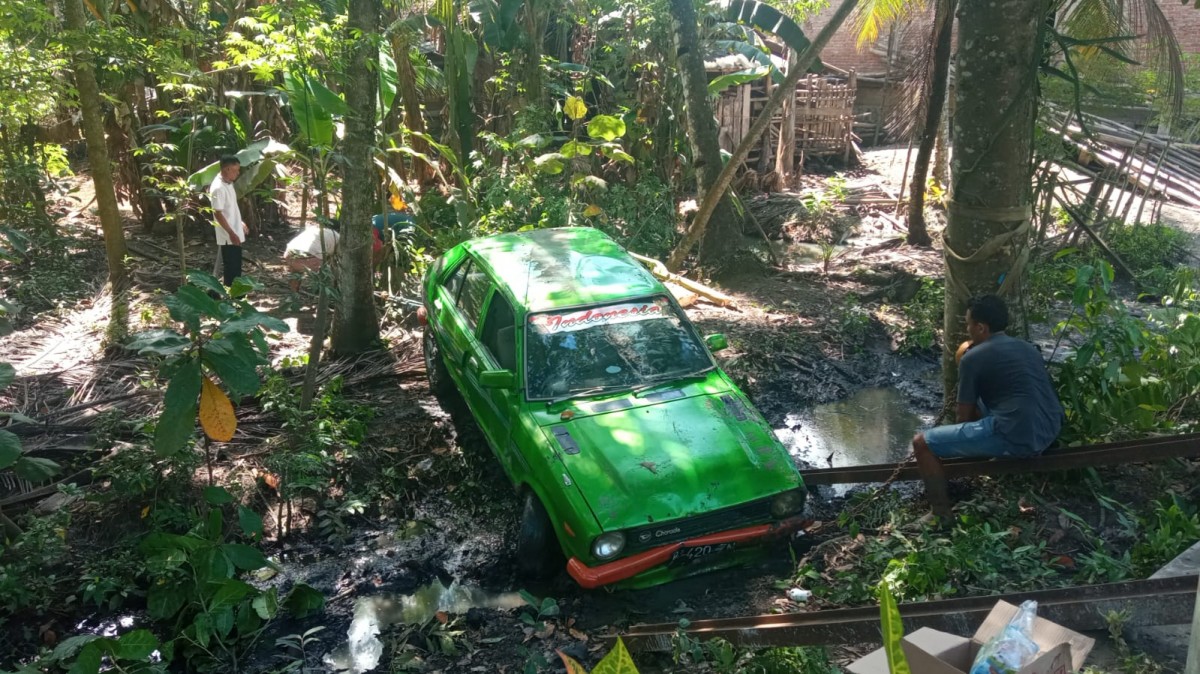 Mobil Daihatsu Charade milik warga Cluring yang terperosok ke parit. (Foto: Eko Purwanto/jatimnow.com)