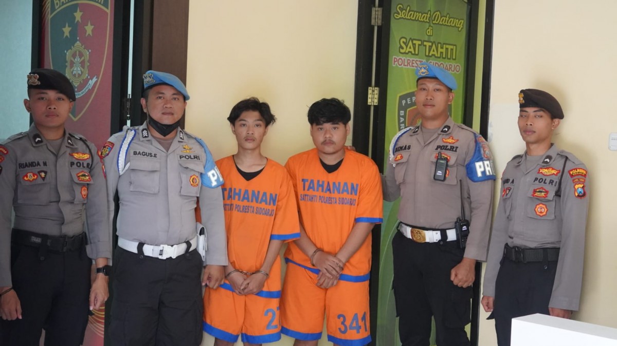 Dua pemuda yang mengacungkan senjata tajam. (Foto: Heri for jatimnow.com)