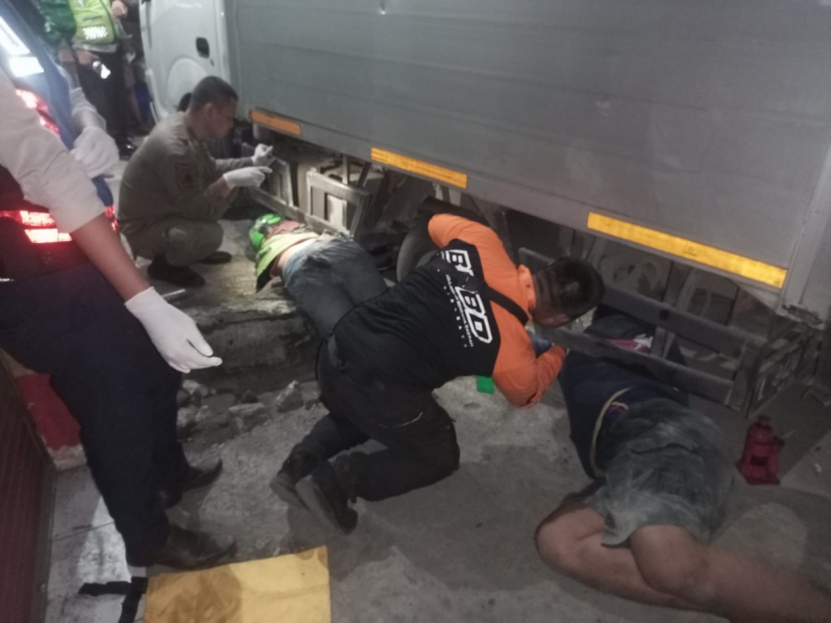 Petugas BPBD Surabaya melakukan evakuasi pengemudi ojol yang terseret mobil boks setelah ditabrak pengendara roda dua yang mabuk. (foto: BPBD Surabaya for jatimnow)