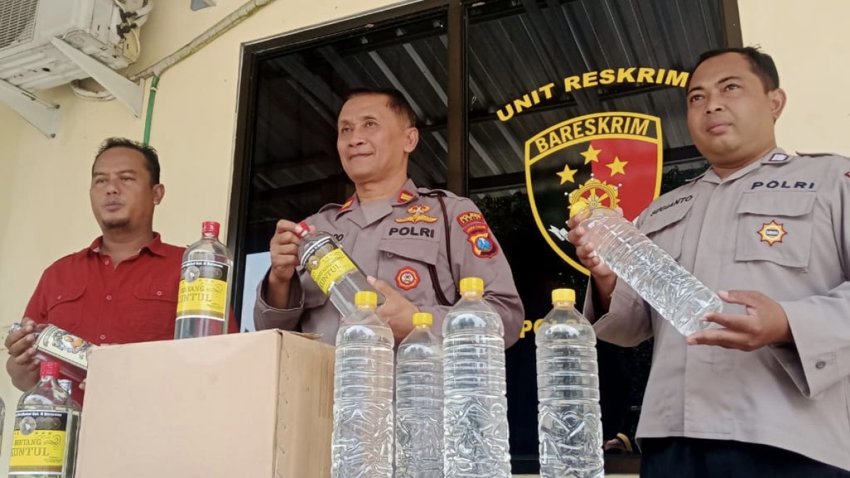 Polisi menunjukkan botol-botol miras hasil razia. (foto : Polsek Pagu for jatimnow.com)