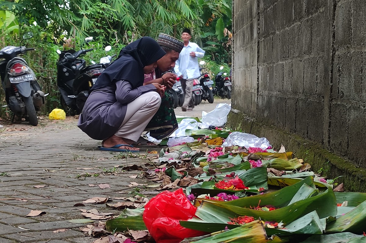 Peziarah di TPU Cluring yang mendoakan para leluhur dari balik tembok makam. (foto: Eko Purwanto/jatimnow.com)