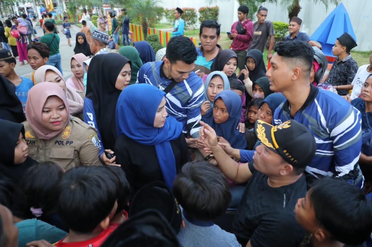 Bupati Sampang Slamet Junaidi dan Ketua TP PKK Mimin Slamet Junaidi membagiikan sembako gratis. (foto: Humas Pemkab Sampang for jatimnow.com)