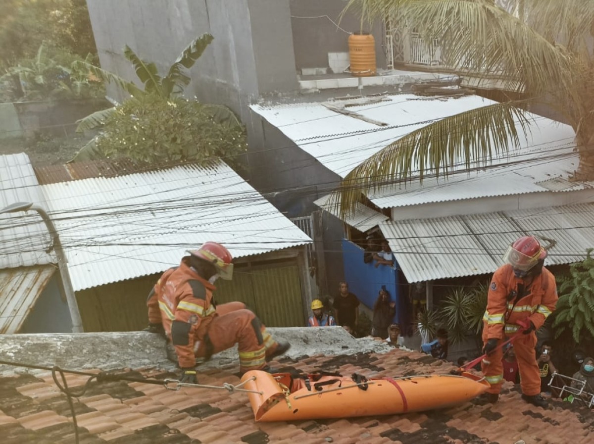 Proses evakuasi jenazah wanita dari rooftop rumahnya (Foto: Dok. BPBD Surabaya)
