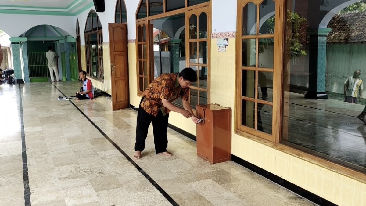 Takmir masjid menunjukkan kotak amal yang baru saja dibobol maling (Foto: Yanuar Dedy/jatimnow.com)