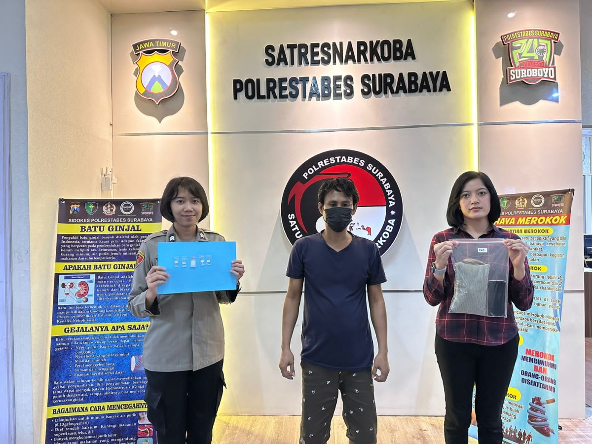 Tersangka EBH diapit petugas Satnarkoba Mapolrestabes Surabaya. (Satnarkoba Polrestabes Surabaya for Jatimnow.com)