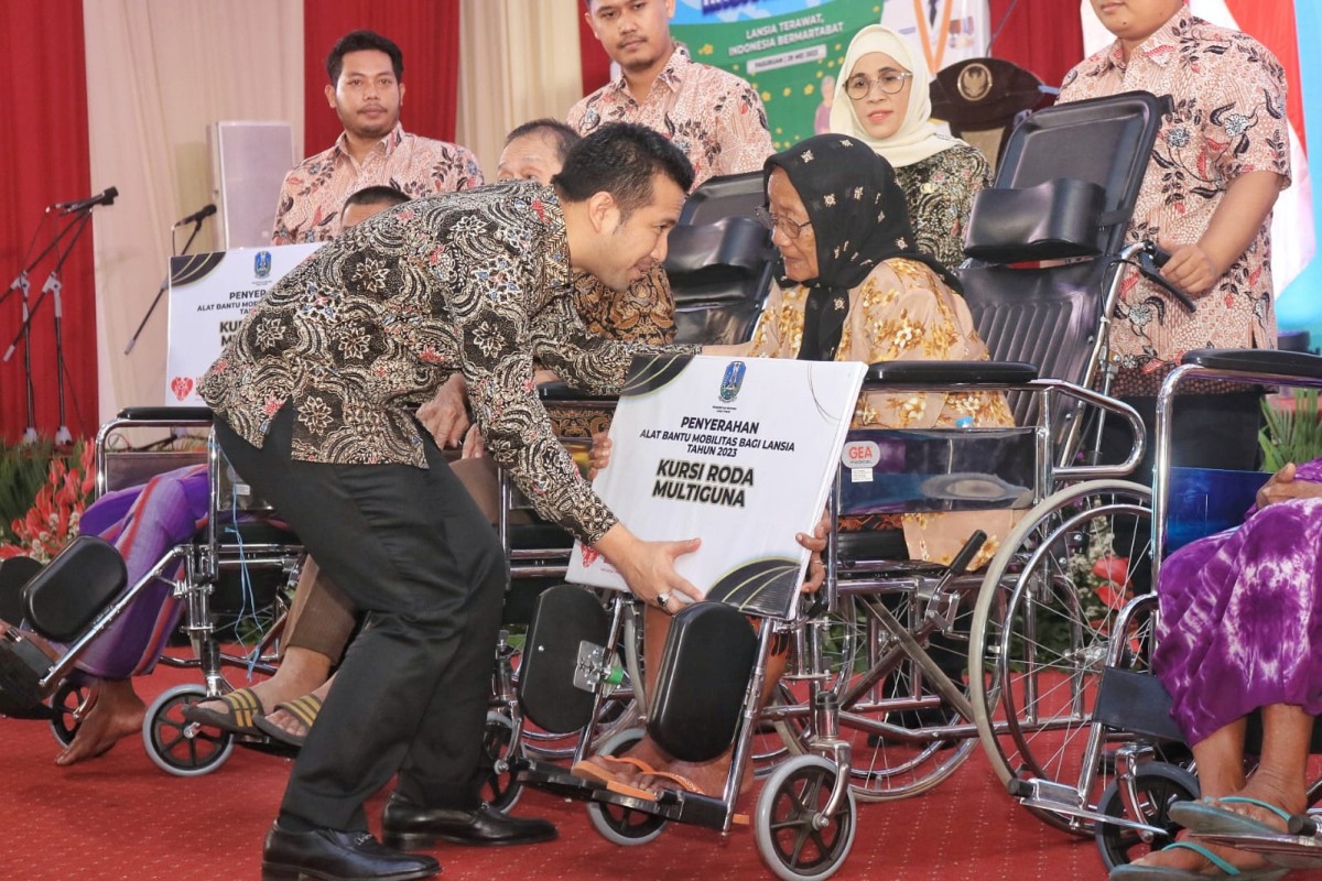 Wakil Gubernur Jawa Timur Emil Elestianto Dardak menyerahkan bantuan kursi roda multi guna pada lansia. (foto: Pemkot Pasuruan for jatimnow.com)