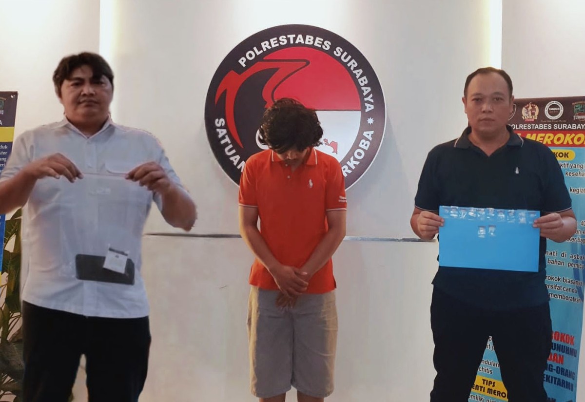 Tersangka MRD diapit petugas Satnarkoba Polrestabes Surabaya.(foto: Satnarkoba Polrestabes Surabaya for jatimnow.com)