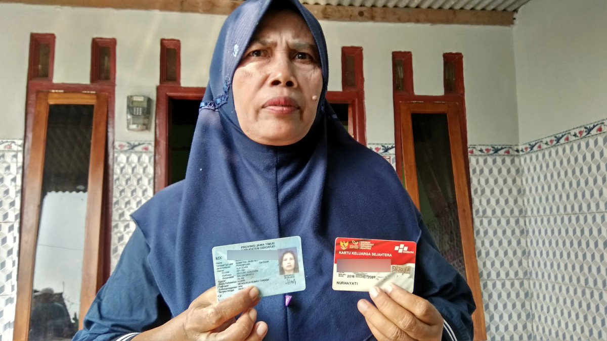Caption: Nurhayati menunjukkan identitas diri dan kartu penerima manfaat. (Achmad Supriyadi/jatimnow.com)