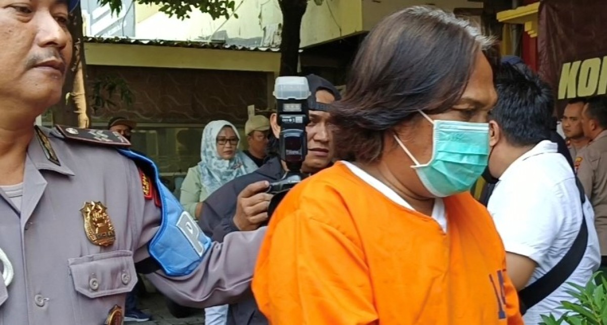 Tersangka Samsul Anang dikawal petugas Polsek Asemrowo.(foto: Rama Indra/jatimnow.com)
