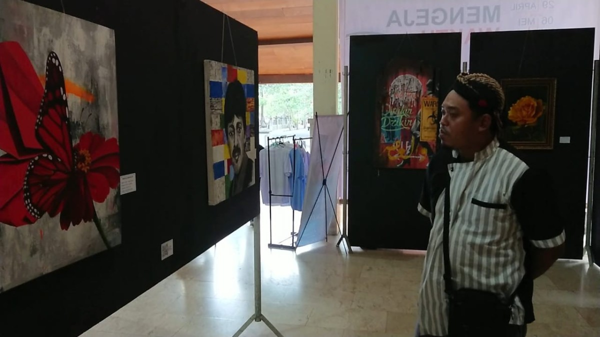 Salah satu pengunjung pameran melihat lukisan Orkes Tanam yang dipamerkan. (foto: Bramanta Pamungkas/jatimnow.com)