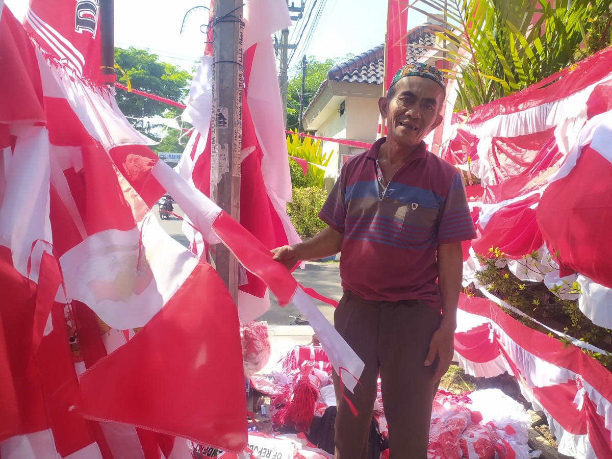 Eem Sulaeman, pedagang pernak-pernik dan bendera asal Garut yang pilih berjualan di Lamongan. (Foto : Adyad Ammy Iffansah/jatimnow.com)