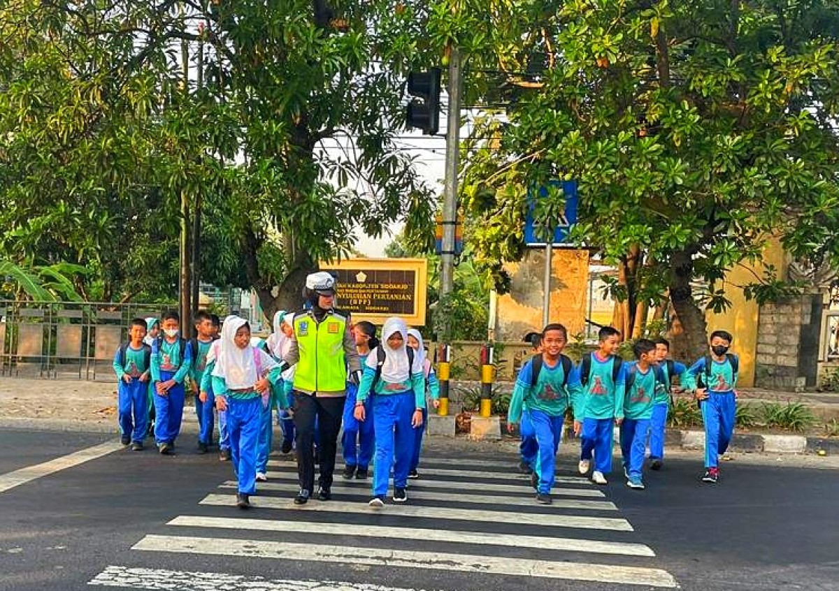 Polwan menyebrangkan sejumlah anak sekolah. (Foto: Polresta Sidoarjo for jatimnow.com)