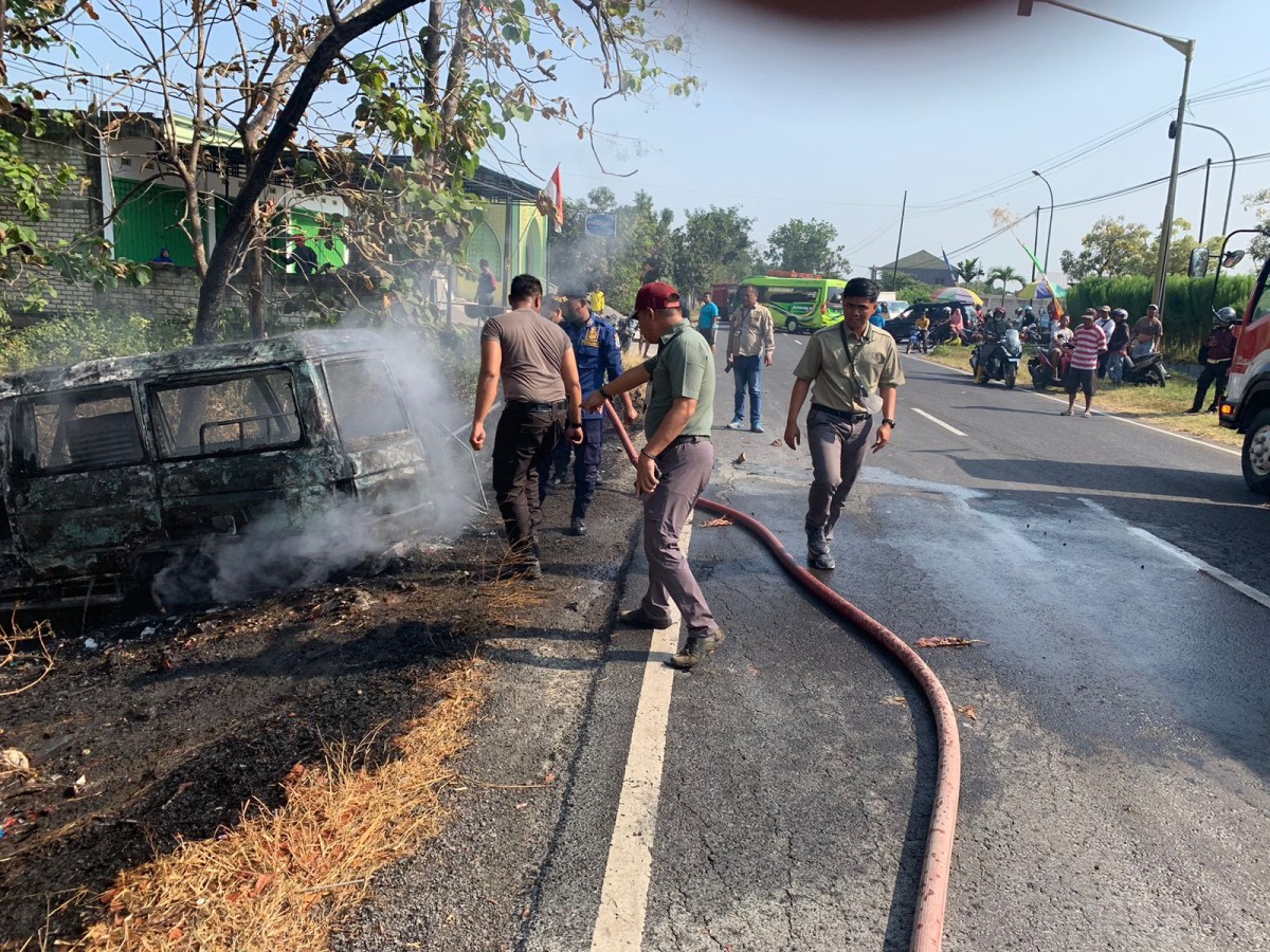 Petugas damkar saat melakukan pembasahan minibis terbakar di Lamongan. (Foto: Damkar Lamongam for jatimnow.com)