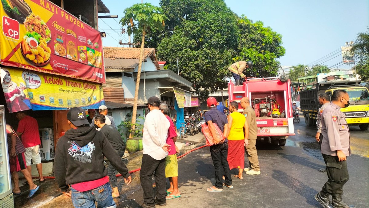 Petugas pemadam melakukan pembasahan di area kebakaran. (Foto : Humas Polres Lamongan for jatimnow.com)