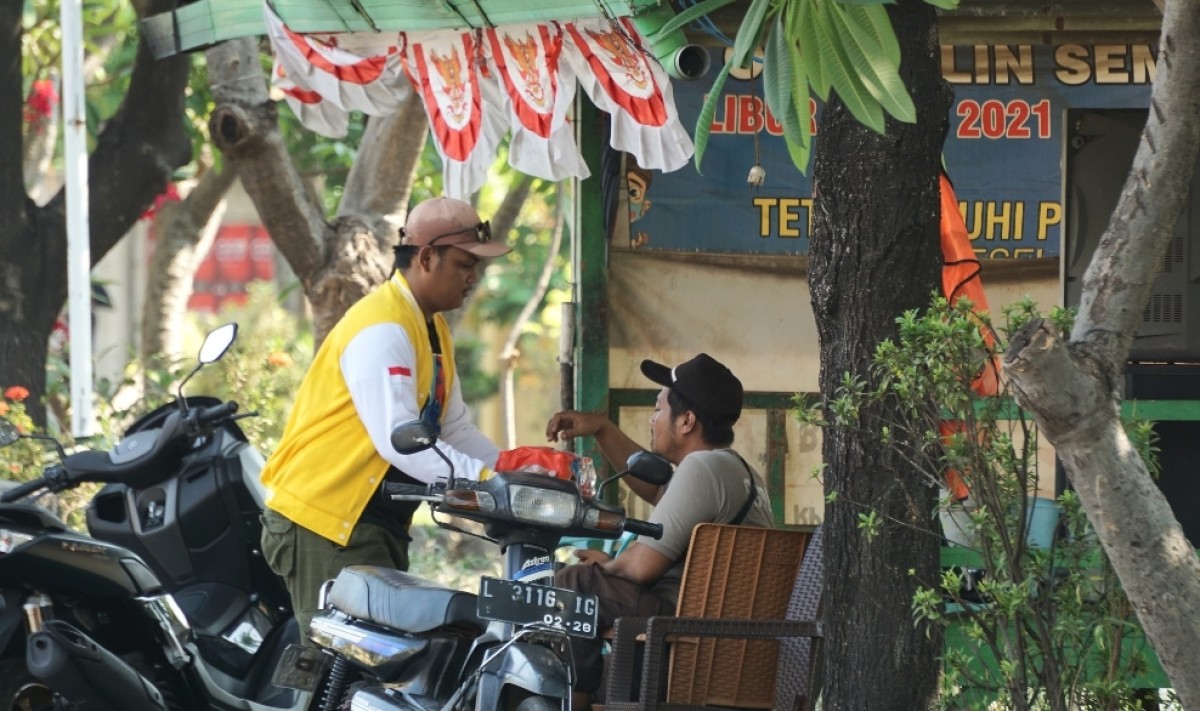 Kader Golkar Surabaya tertangkap kamera membagikan air mineral ke Warga Bulak, Surabaya. (Foto: Ni'am Kurniawan/jatimnow.com)