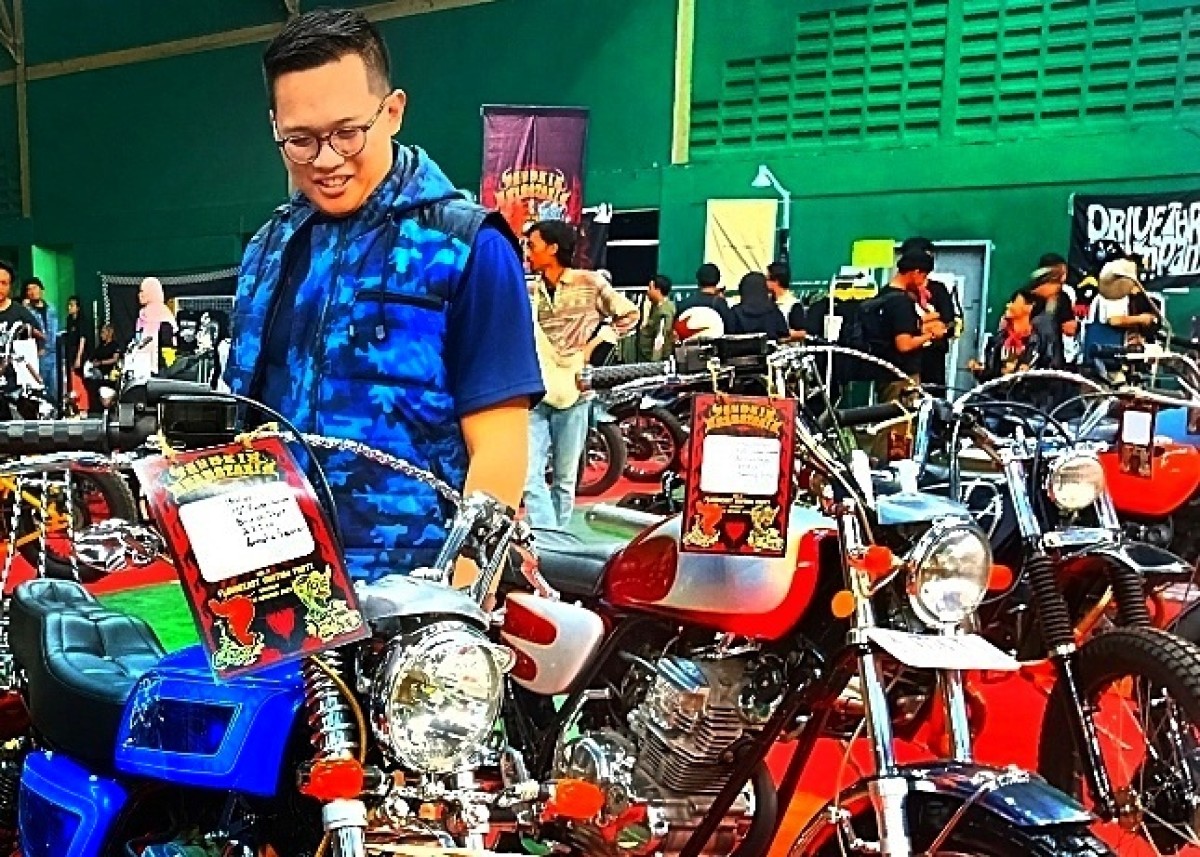 M. Ali Affandi saat mengamati motor costum PDT Garage 18 di Tangkis Bermotoria IV Sidoarjo.
