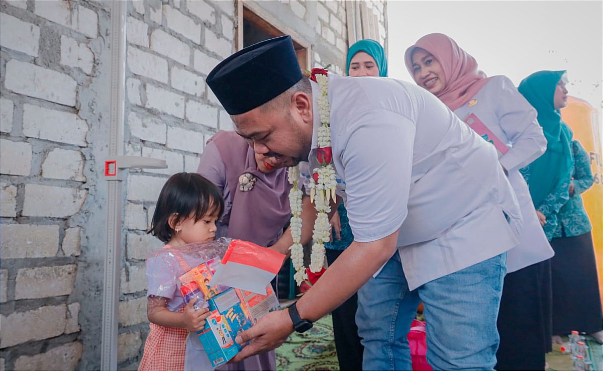 Bupati Gresik Fandi Akhmad Yani dan Ketua TP PKK Nurul Haromaini Ali sedang memberikan makanan tambahan kepada anak-anak. (Foto: Humas Pemkab Gresik for jatimnow.com)