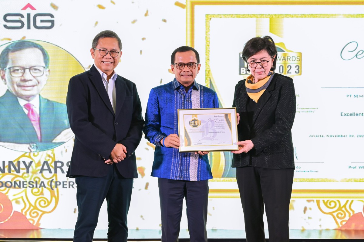 Komisaris Bisnis Indonesia, Dorothea Samola (kanan) menyerahkan penghargaan The Best CEO: Excellent in Encourage Risk Taking kepada Direktur Utama SIG, Donny Arsal (tengah), didampingi dewan juri Top CEO BUMN Awards 2023, Rudiantara (kiri), pada ajang Bis