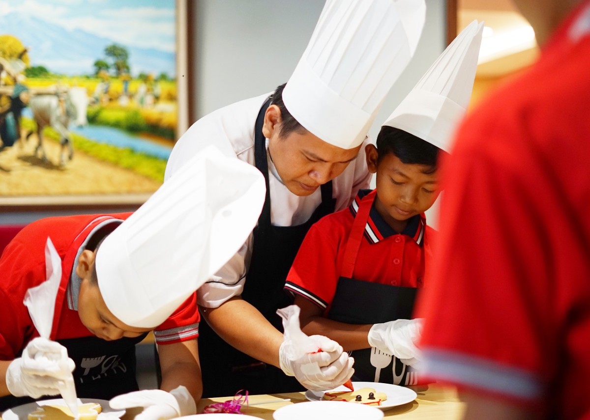 Chef Favehotel Sidoarjo dengan antusias memandu anak-anak dari Panti Asuhan Dorkas dalam menghias kue jahe yang lezat. (Foto: Ahaddiini HM/jatimnow.com)..