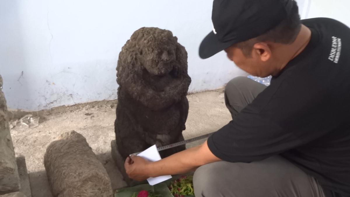 Yasin membersihkan Arca Dwarapala yang ditemukannya. (Foto: Bramanta Pamungkas/jatimnow.com)