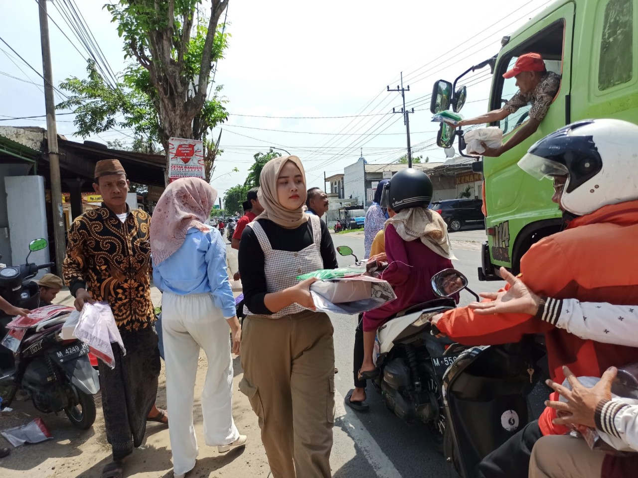 Relawan Prabowo-Gibran membagikan jas hujan dan makanan ke para pengendara motor.  Sumber: jatimnow.com https://jatimnow.com/baca-64995-relawan-prabowogibran-bagibagi-jas-hujan-ke-pengendara-di-bangkalan. (Foto: Fathor Rahman/jatimnow.com)