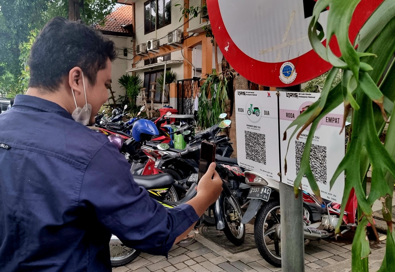 Pengguna parkir tepi Jalan saat melakukan scan pembayaran QRIS. (Foto: Ni'am Kurniawan/jatimnow.com)