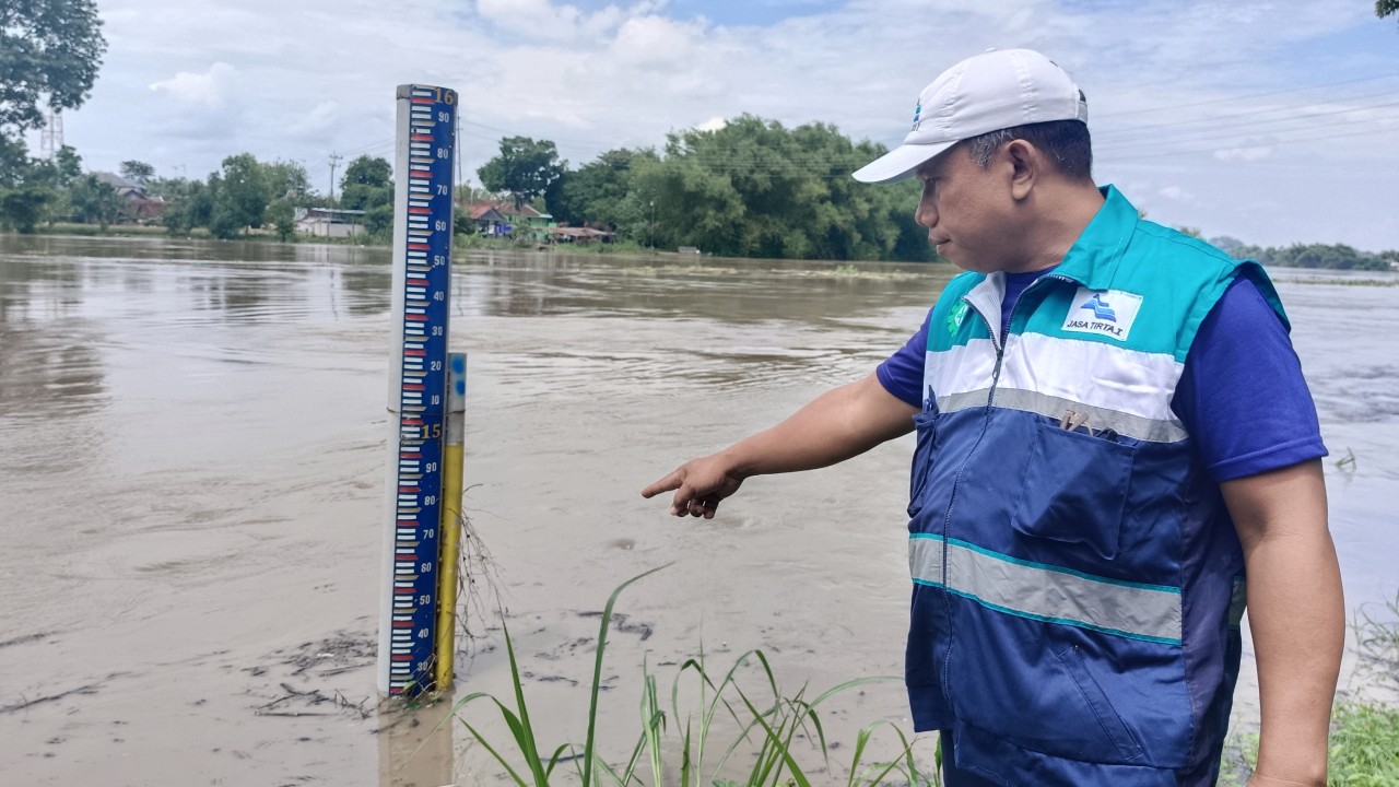 Ali Susanto, pembaca tinggi muka air Perum Jasa Tirta Wilayah Sungai Bengawan Solo saat menunjukkan papan pengamatan tinggi muka air. (Foto: Misbahul Munir/jatimnow.com)