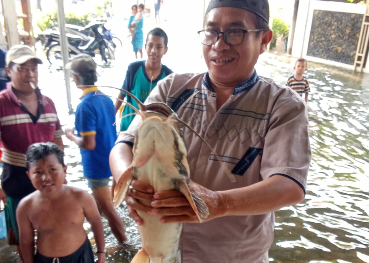 Salah satu warga menangkap lele super jumbo di Desa Trosobo Taman Sidoarjo. (Foto: Ahaddiini HM/jatimnow.com)