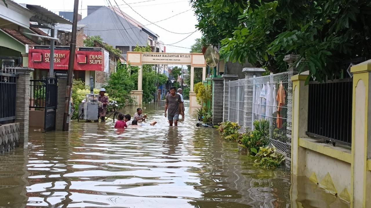 Anak-anak asik main air banjir sambil jajan di Desa Kalianyar Kecamatan Kapas. (Foto: Misbahul Munir/jatimnow.com)