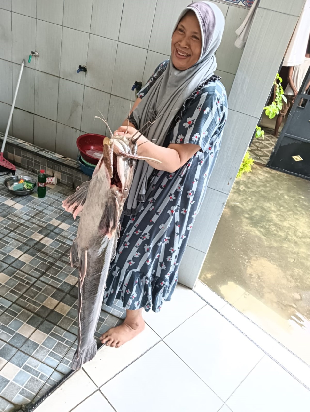 Salah satu warga menangkap lele super jumbo di Desa Trosobo Taman Sidoarjo. (Foto: Ahaddiini HM/jatimnow.com).