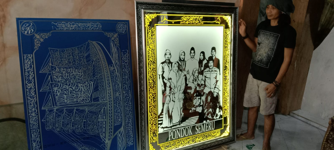 Shodiqun saat menunjukan karyanya dalam medium kaca. (Foto: Adyad Ammy Iffansah/jatimnow.com)