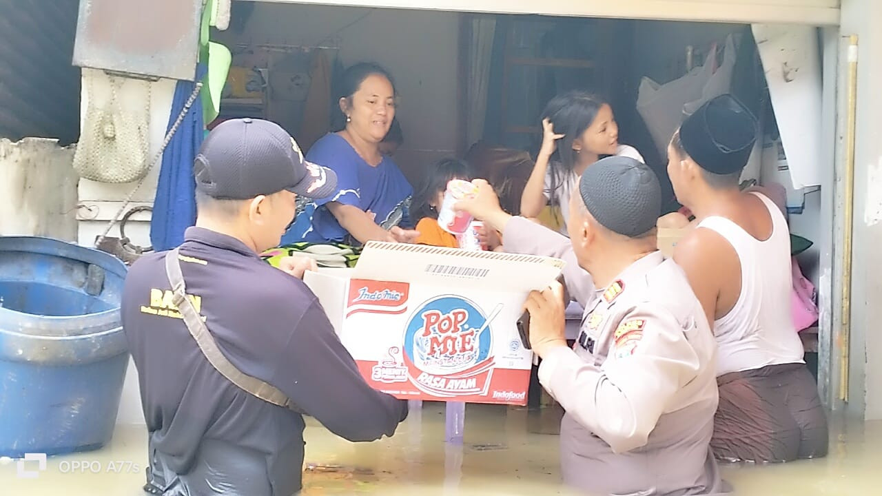 Petugas kepolisian saat memberikan bantuan pada warga terdampak banjir. (Foto: Humas Polres Sampang)