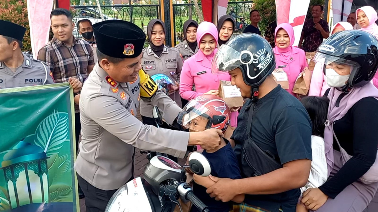 Kapolres Trenggalek, AKBP Gathut Bowo Supriyono saat memasangkan helm. (Foto: Bramanta Pamungkas/jatimnow.com)