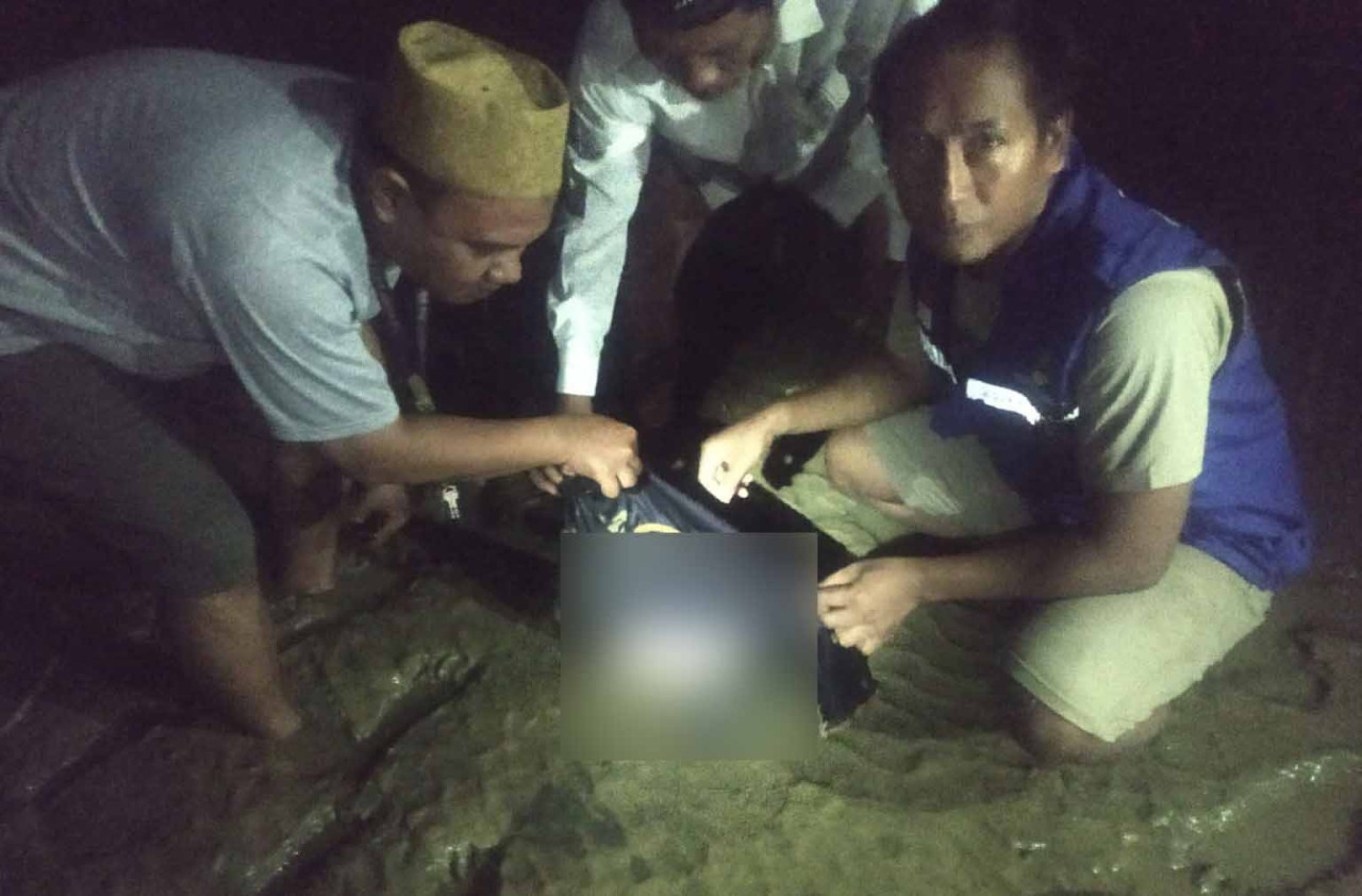 Petugas mengevakuasi mayat bayi di tepi pantai (Foto: Mulyadi for jatimnow.com)