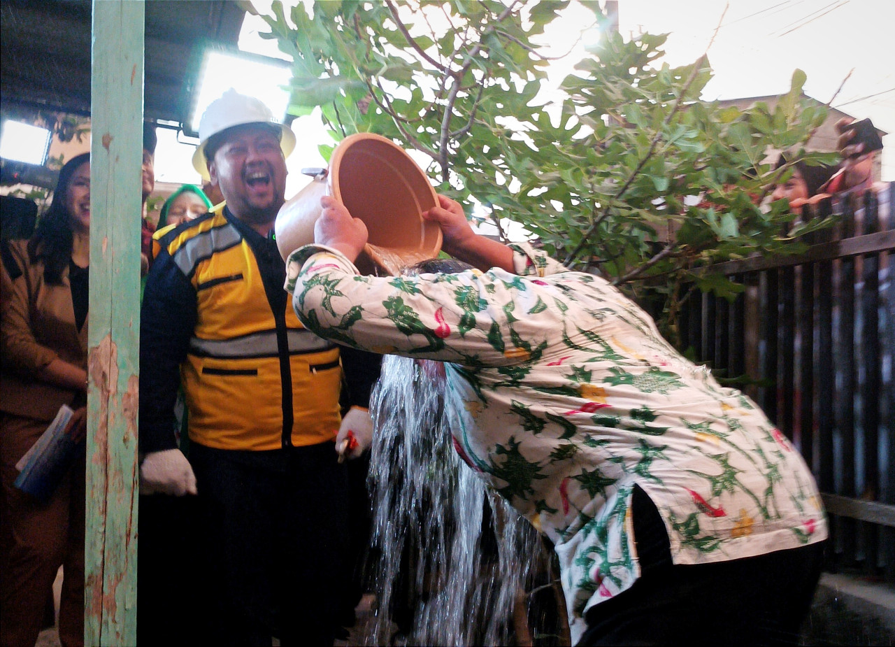 Kepala Desa Wadak Lor, Kecamatan Duduksampeyan, Kabupaten Gresik, Saiful Arif saat menyiram air tubuhnya di depan Bupati Gresik Fandi Akhmad Yani. (Foto: Sahlul Fahmi/jatimnow.com)