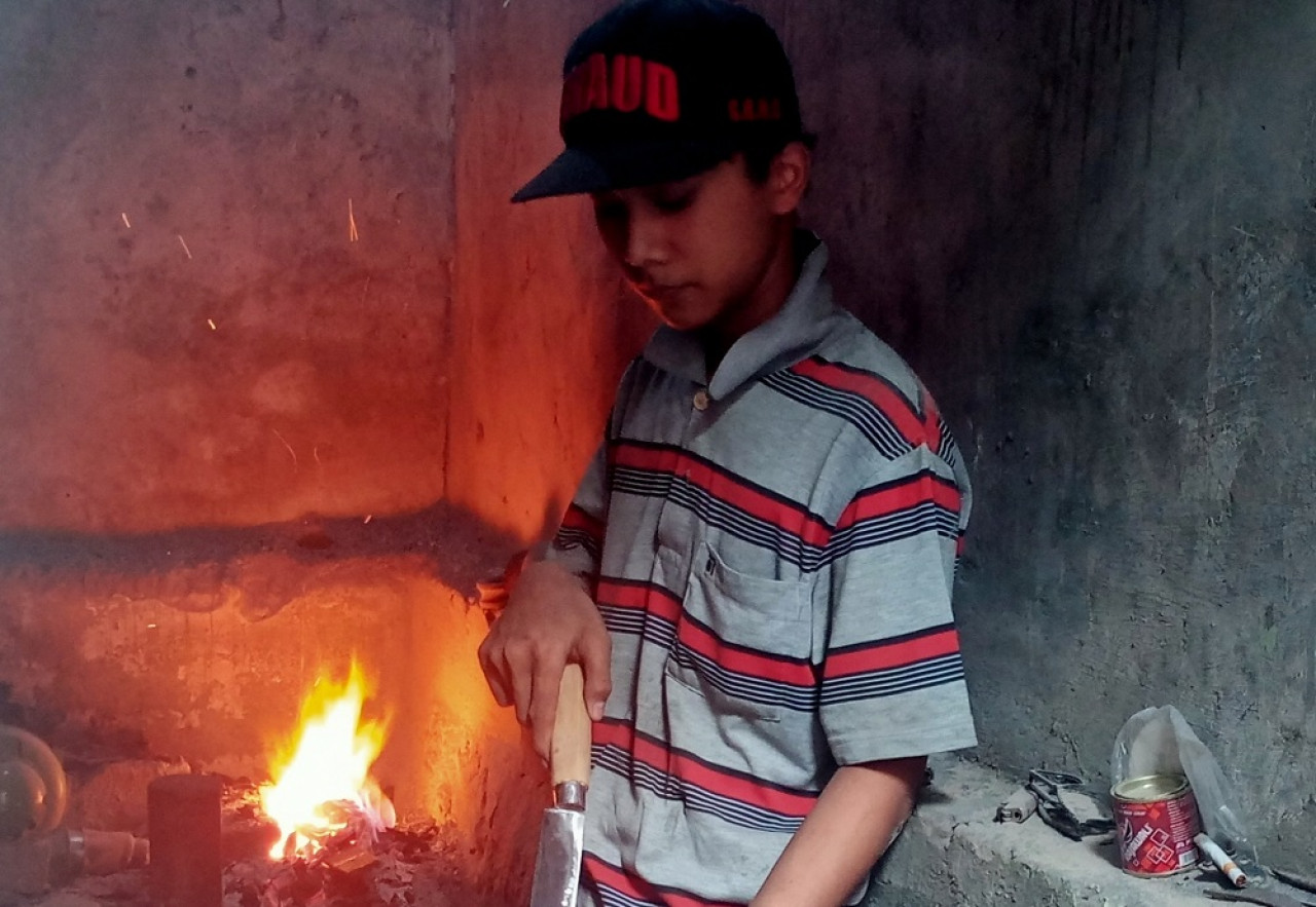 Muhammad Alan, pandai besi sedang menggarap di bengkel kerjanya, Jalan Binor Bawah 8 B RT 10 RW 14 Kecamatan Blimbing, Kota Malang. (Foto: Gerhana/jatimnow.com)