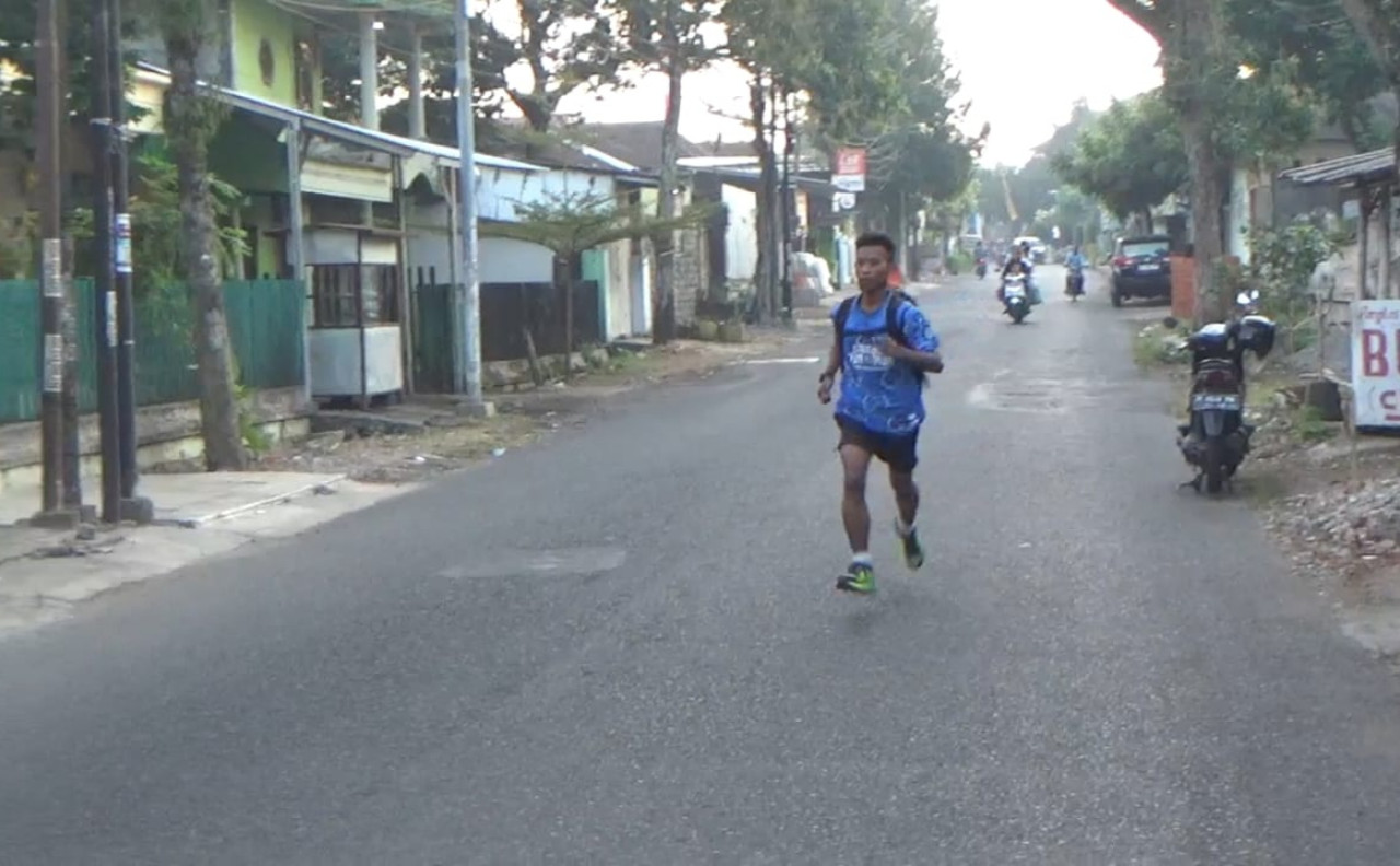Alif Fathurrohman berlari ke titik penjemputan mobil sekolah. (Foto: Dhika for jatimnow.com)