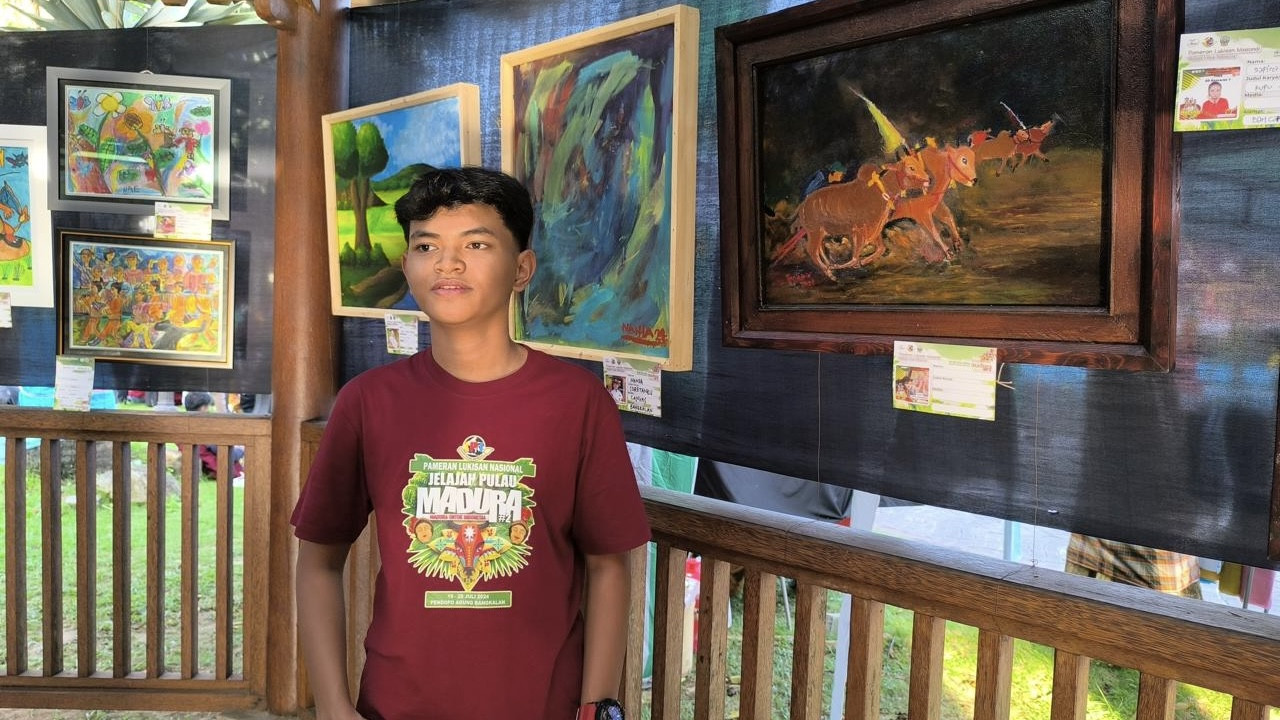 Salah satu pengunjung berfoto di depan lukisan dalam Pameran Jelajah Madura 2. (Foto: Fathor Rahman/jatimnow.com)