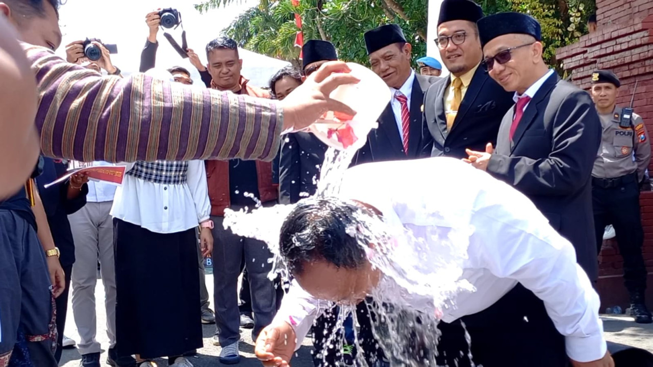 Mahasiswa saat mengguyur anggota DPRD Trenggalek terlantik dengan air kembang. (Foto: Bramanta Pamungkas/jatimnow.com)