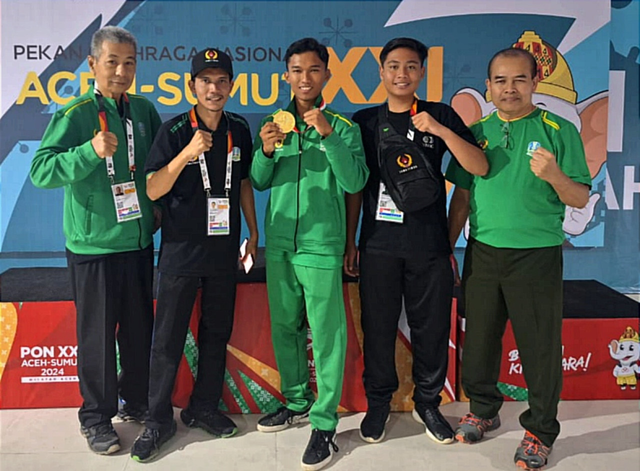 Atlet tembak Jatim Luqman Syarif Ramadhani (tengah) foto bersama official seusai upacara penghormatan pemenang kelas 18-41 meter metallic silhouette multiring PON XXI Aceh Sumut 2024. (Foto: KONI Jatim).