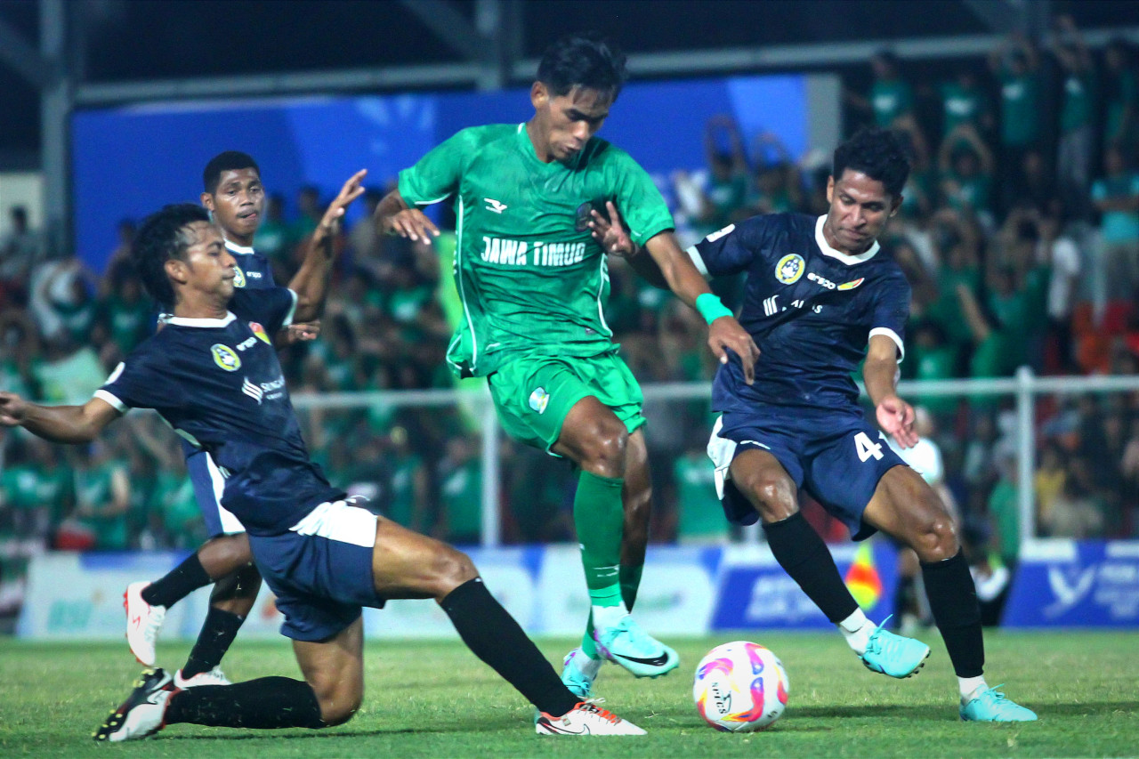 Penyerang tim sepak bola Jatim Wigi Pratama dihalau beberapa pemain NTT dalam laga perempat final PON XXI Aceh-Sumut 2024. (Foto: Sahlul Fahmi/jatimnow.com)