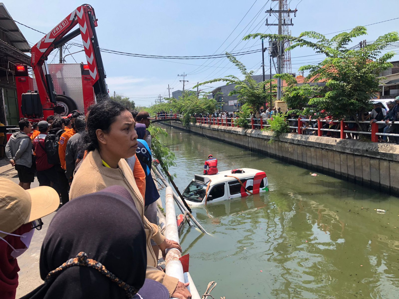 Petugas dari Damkar Surabaya saat evakuasi mobil Wira Wiri Suroboyo yang nyemplung di sungai. (Foto: Rizki for jatimnow.com)
