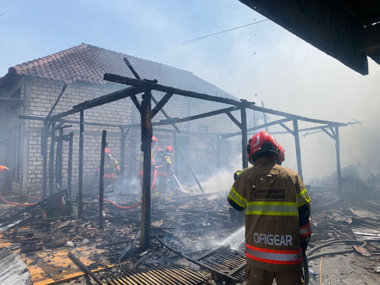 Petugas Damkar Bojonegoro saat melakukan pembasahan di rumah yang terbakar. (Foto: Damkarmat Bojonegoro)