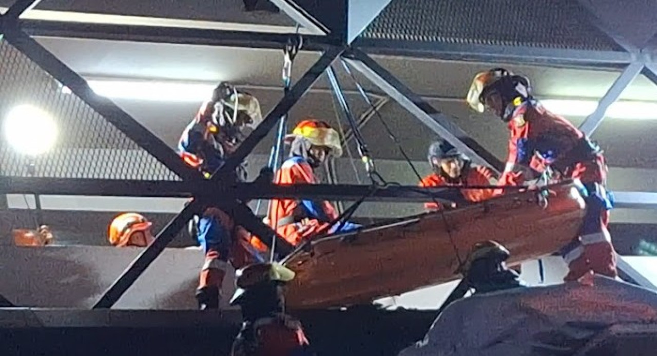 Petugas Damkar Surabaya tengah berusaha mengevakuasi jenasah korban dari atap teras lobi hotel. (Foto: Misbahul Munir/jatimnow.com)